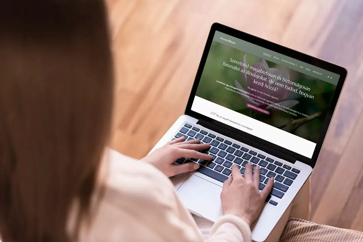 Nő laptopon dolgozik, AromaMami weboldalra kattintva.
